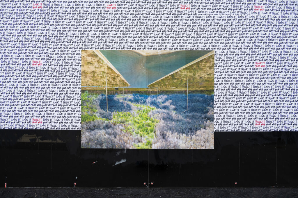 Colour Photograph of photo montage art pasted up on a black wall with white paper and the words "have it your way" repeated in the background.