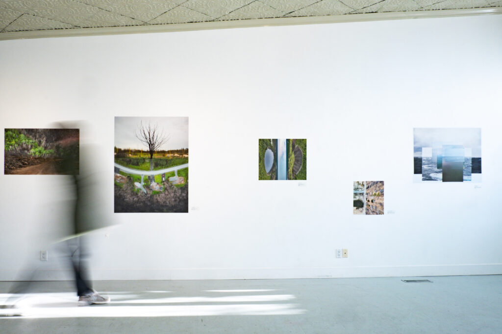 A colour photograph of a gallery wall with art on the white wall.