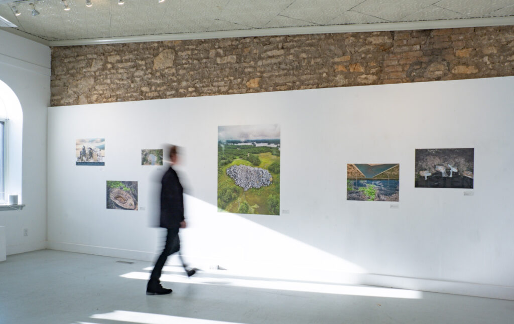 A colour photograph of a gallery wall with art on the white wall.